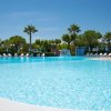 Piscina all'aperto con lettini e palme.