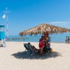 Spiaggia con ombrellone di paglia e bagnini.