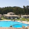 Piscina azzurra con bungalow e alberi intorno.