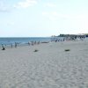 Lunga spiaggia sabbiosa con bagnanti distanti.