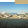 Spiaggia con lettini e ombrelloni bianchi.