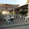 Area all'aperto con sedie bianche e ombrelloni in un ristorante.