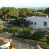 Una casa bianca circondata da alberi e vegetazione, con un'auto parcheggiata nel giardino.