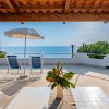 Terrazza con ombrellone, sedie e vista mare.