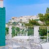 Terrazza con tavoli bianchi e vista su città collinare.