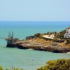 Costa rocciosa con mare blu e costruzione.
