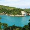 Baia con acqua turchese e scogliera.