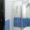 Bagno con doccia, piastrelle blu e asciugamani bianchi.