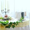 Tavolo decorato con tovaglia bianca e foglie verdi.