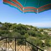 Vista sul mare da una terrazza con ombrellone verde.