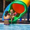 Bambino su scivolo acquatico colorato con un adulto.