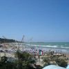 Spiaggia affollata con ombrelloni e mare ondoso.