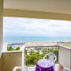 Un balcone con due sedie bianche e vista sul mare e sulla spiaggia con ombrelloni.