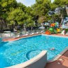 Piscina all'aperto circondata da lettini e alberi.