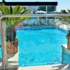 Piscina con piante in vaso e lettini sullo sfondo.