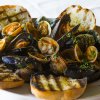 Cozze e vongole con crostini su un piatto bianco.