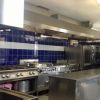 Cucina industriale con piastrelle blu e attrezzature in acciaio inox.