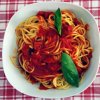 Spaghetti al pomodoro con basilico in un piatto bianco.