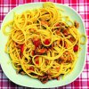 Spaghetti con frutti di mare e pomodorini in un piatto bianco.