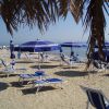 Spiaggia sabbiosa con lettini e ombrelloni blu.