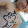 Bambino sorridente con disegno di zebra dipinto sul torace.