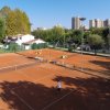 Campi da tennis all'aperto con giocatori e ombrelloni.