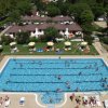 Una piscina con persone che nuotano e prendono il sole.