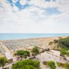 Spiaggia con file di ombrelloni vicino a una strada e alberi.
