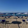 Spiaggia con ombrelloni a righe blu e bianche.