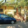 Un'auto blu parcheggiata davanti a una casa gialla con alberi attorno.