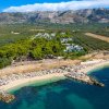 Spiaggia affollata con mare blu e colline sullo sfondo.