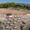 Spiaggia con ombrelloni bianchi, sdraio e canoe arancioni.