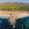 Una spiaggia con ombrelloni e mare cristallino, vista dall'alto.