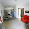 Soggiorno con cucina, tavolo, e divano rosso.