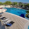Piscina circondata da lettini e ombrelloni su una terrazza in legno.