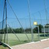 Campo da calcio recintato, con rete alta e cancello d'ingresso.