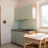 Cucina compatta con mobili verdi, tavolo e finestre luminose.