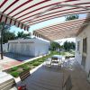 Terrazza esterna con tende a strisce e tavolo da pranzo.