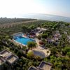 Villaggio con piscina e case in mezzo al verde, vicino al mare.