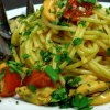 Un piatto di spaghetti con cozze, pomodorini e prezzemolo fresco.
