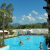 Persone in piscina sotto il cielo azzurro con ombrelloni bianchi.