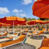 Ombrelloni arancioni e lettini su una spiaggia sabbiosa sotto un cielo azzurro.