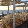 Ristorante all'aperto in riva al mare con sedie bianche.