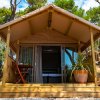 Tenda glamping con veranda e tavolo in legno.
