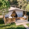 Tenda glamping con veranda in legno in un'area verde.