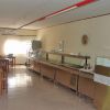 Sala da pranzo semplice con tavoli, sedie e banco self-service.