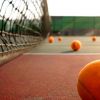 Un campo da tennis con palline arancioni sparse vicino alla rete.