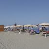Ombrelloni e lettini sulla spiaggia sabbiosa, cielo sereno.