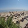 Spiaggia gremita con ombrelloni a strisce.