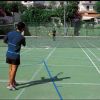 Due persone giocano a tennis su un campo all'aperto.